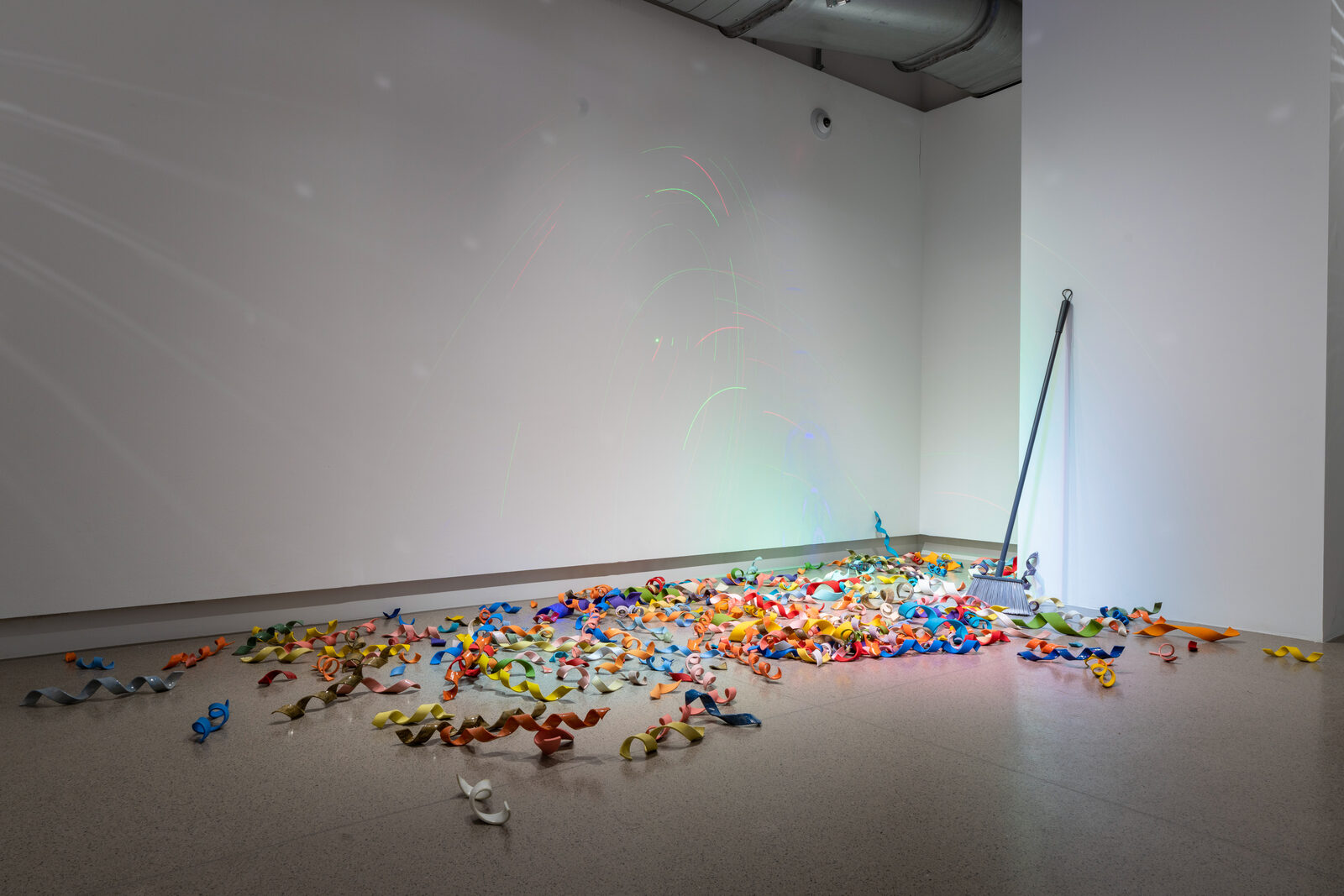Confetti, hand-built ceramic confetti scattered across the gallery floor beside a found broom