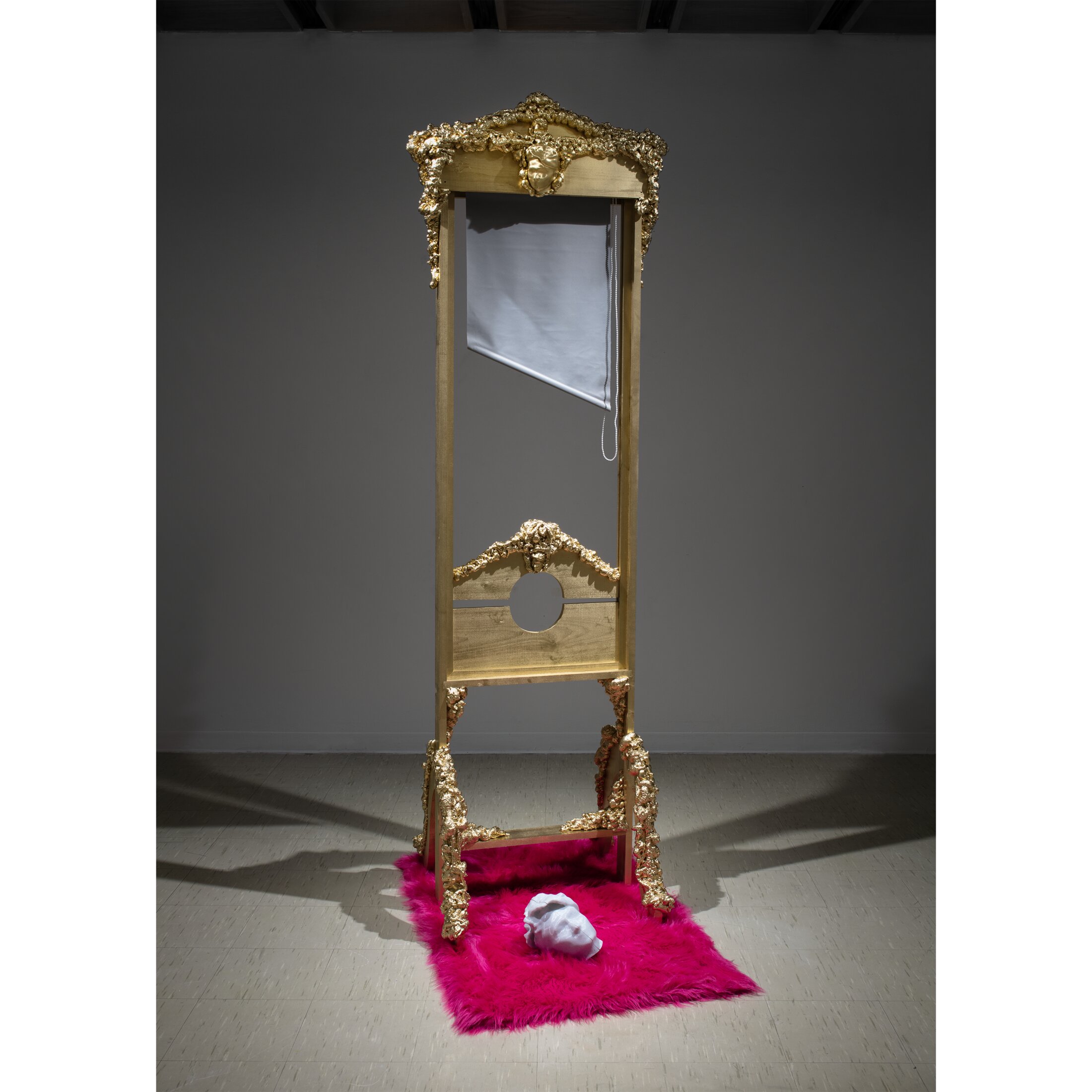 Self-Portrait Blinds to LIVE, a gilded Rococo guillotine sculpture with a small cast head resting on hot-pink faux fur